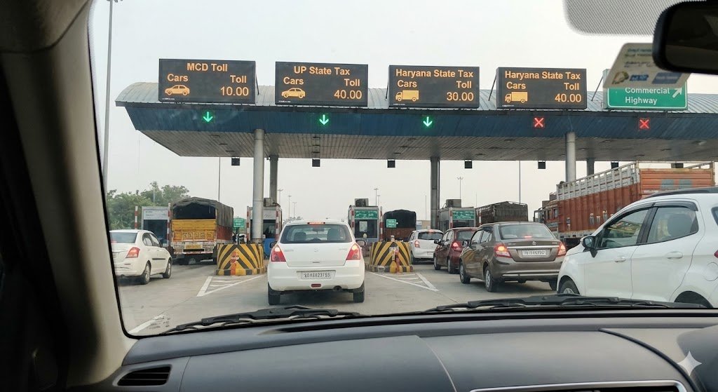 Booking a Cab in Noida? 5 Things You Must Know Before Your Next Ride a view from inside a car at a toll plaza showing various state tax and mcd toll charges, illustrating hidden costs in cab travel.